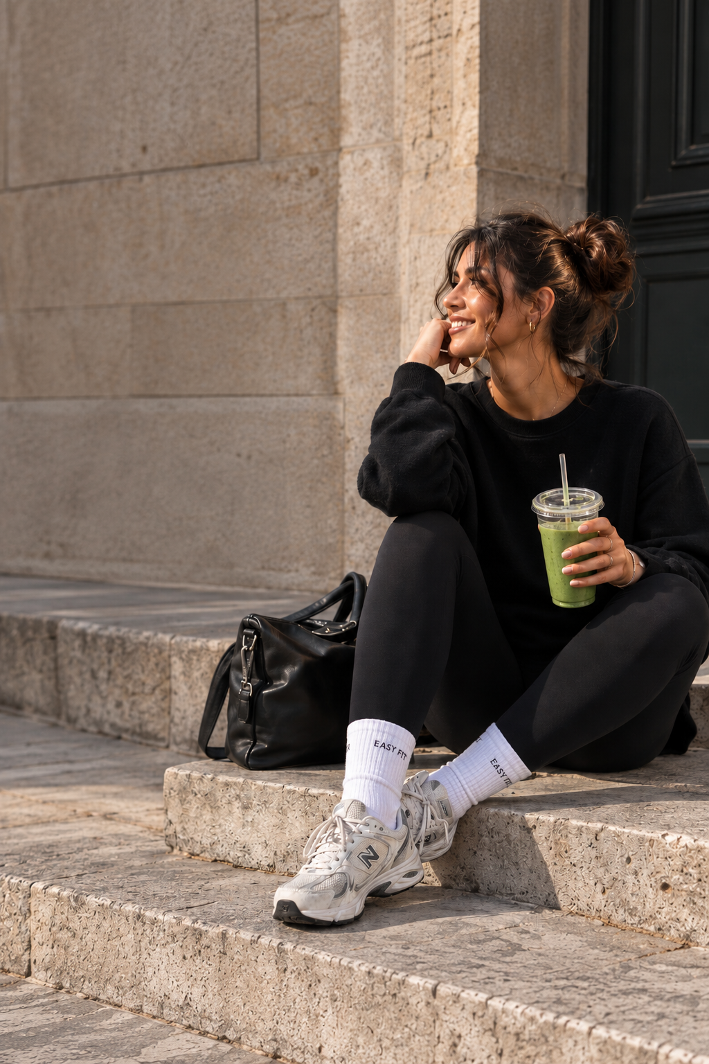 Femme EASY FIT assise sur des marches en pierre, legging noir et boisson fraîche